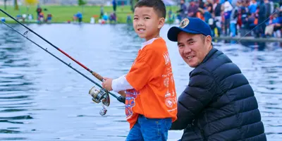 Boy and man fishing at Knabe Park lake, looking to camera