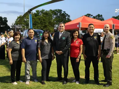 Cerritos City Council and special guests at National Night Out 2026, in front of the Sky Night helicopter. From left: Councilmember Sophia M. Tse, Mayor Pro Tem Mark E. Pulido, Mayor Lynda Provido Johnson, Los Angeles County Sheriff Robert G. Luna, Councilmember Jennifer Hong, Councilmember Frank Aurelio Yokoyama, and Cerritos Sheriff Station Captain Dru Strong.